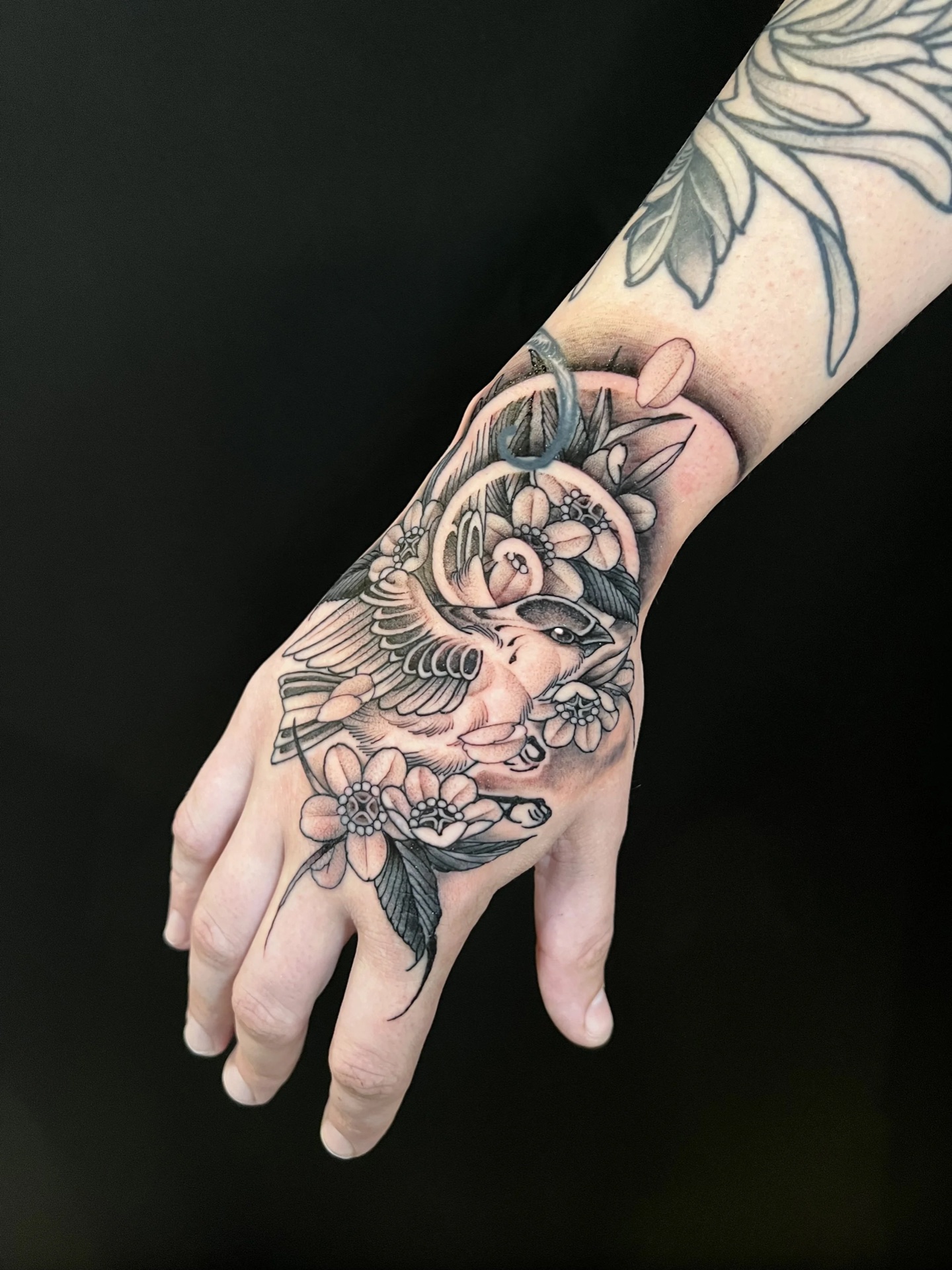 Black and grey bird and blossom hand tattoo tattoo by Levi Taylor